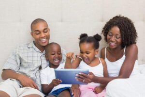 Família sentada na cama assistindo algo no iPad
