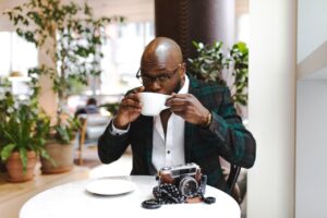 Homem negro em um café com uma câmera na mesa